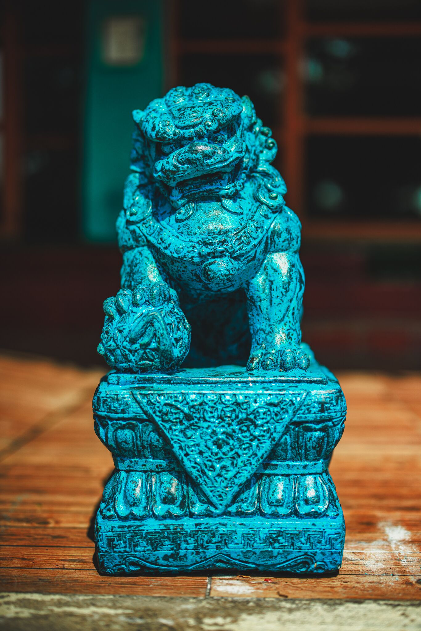 A blue lion statue on a wooden base.