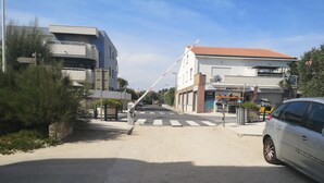 Una entrada protegida con barrera automática, un edificio con techo de tejas rojas y un automóvil estacionado.