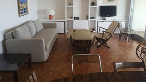 Una sala de estar con un sofá, una mesa de centro, un televisor y un comedor con sillas y una mesa.