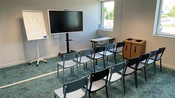 A conference room with a whiteboard, a large flat-screen TV, and several chairs arranged around a table.