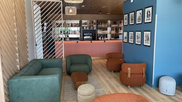 Un área de descanso moderna con asientos, un bar y cuadros en la pared.