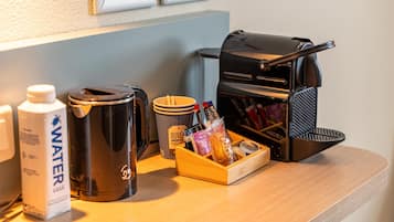 Una kitchenette con cafetera, una botella de agua, una taza y una bandeja con aperitivos.