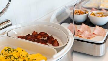 Un buffet de petit-déjeuner avec du bacon, des œufs brouillés et du jambon.