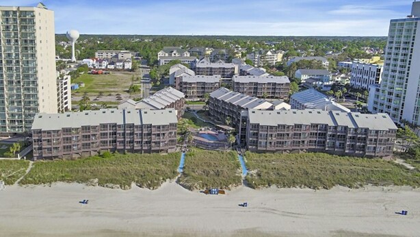 A coastal hotel complex with multiple buildings, a beach in the foreground, and a clear sky. - Tilghman 146- 3BR Condo- Close to Main St (North Myrtle Beach)