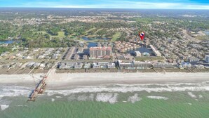 An aerial view of a coastal town with a large hotel, a pier, and a beach.