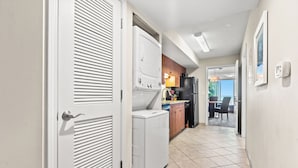 A narrow hallway with a laundry area, a kitchen with wooden cabinets, and a dining area with a view.