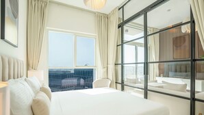 A hotel room with a large bed, a view of the city, and a balcony with a sofa. - Luxury Brand New 2BR Apt at Dubai Hills (Dubai)