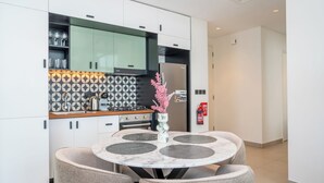 A modern kitchen with white cabinets, a patterned backsplash, and a round dining table with placemats. - Luxury Brand New 2BR Apt at Dubai Hills (Dubai)