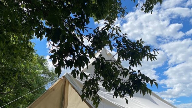 A large, beige tent with a triangular peak, situated on a wooden deck.