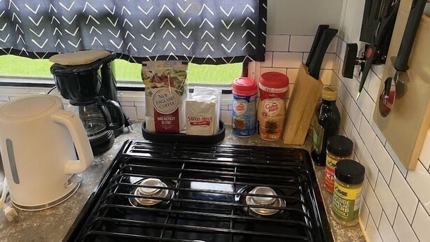 A kitchen with a gas stove, coffee maker, and various coffee and spice containers. - Wine Country Bell Tent w/ King Bed (Lodi)