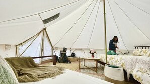 Tienda de campaña con una cama, una mesa y una persona sentada.