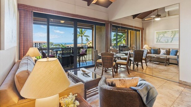 A spacious living area with a large window overlooking the ocean, furnished with a sofa, chairs, and a coffee table.