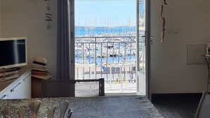 Une chambre avec vue sur un port de plaisance, une table agrémentée d’un vase décoratif et un téléviseur posé sur un meuble.