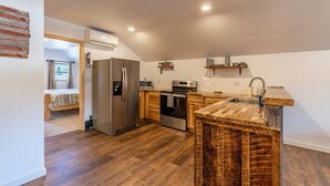 A compact kitchen with a refrigerator, oven, microwave, and wooden cabinets. - Custer`s Loft at Gold Valley Camp| 1 Bed, 1 Bath (Custer)