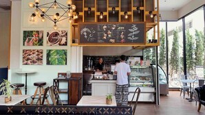 Un café modern amb un mostrador de fusta, un menú escrit a la pissarra i una zona de seients amb taules i cadires.