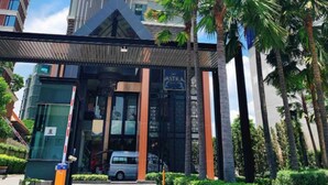 Un edifici modern amb una façana única, un vestíbul cobert i palmeres al primer pla.