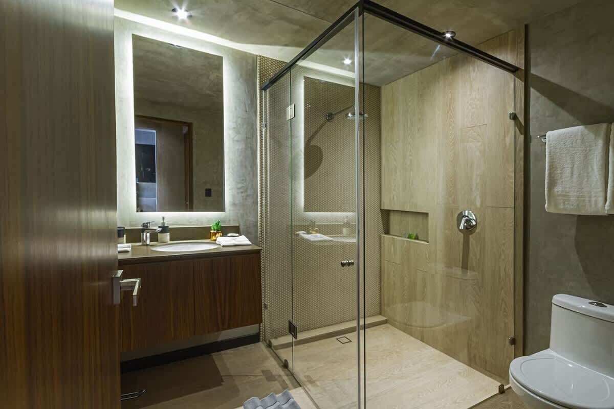 A modern bathroom with a glass-enclosed shower, a wooden vanity, and a white toilet.