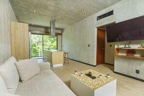 A modern living room with a sofa, a coffee table, and a flat-screen TV mounted on the wall.