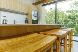 A modern kitchen with wooden countertops, a built-in oven, and a large window overlooking greenery.
