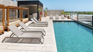 A rooftop pool area with lounge chairs, a wooden pergola, and a clear view of the ocean. - Relaxing 1 BDRM, 1 BR, Balcony & Pool Access Apt (Tulum)