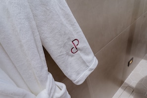 A white towel with a red letter 'P' hanging on a beige tiled wall. - Primo Cabana - Hospedagem na Vinícola (Quatro Barras)