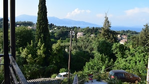 A view from a balcony overlooking a lush green landscape with trees and a distant mountain range. - Ethra Casa (Corfu)