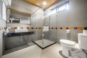 A modern bathroom with a glass-enclosed shower, a white toilet, and a tiled backsplash. - Kenting Kavana Cottage (Hengchun)