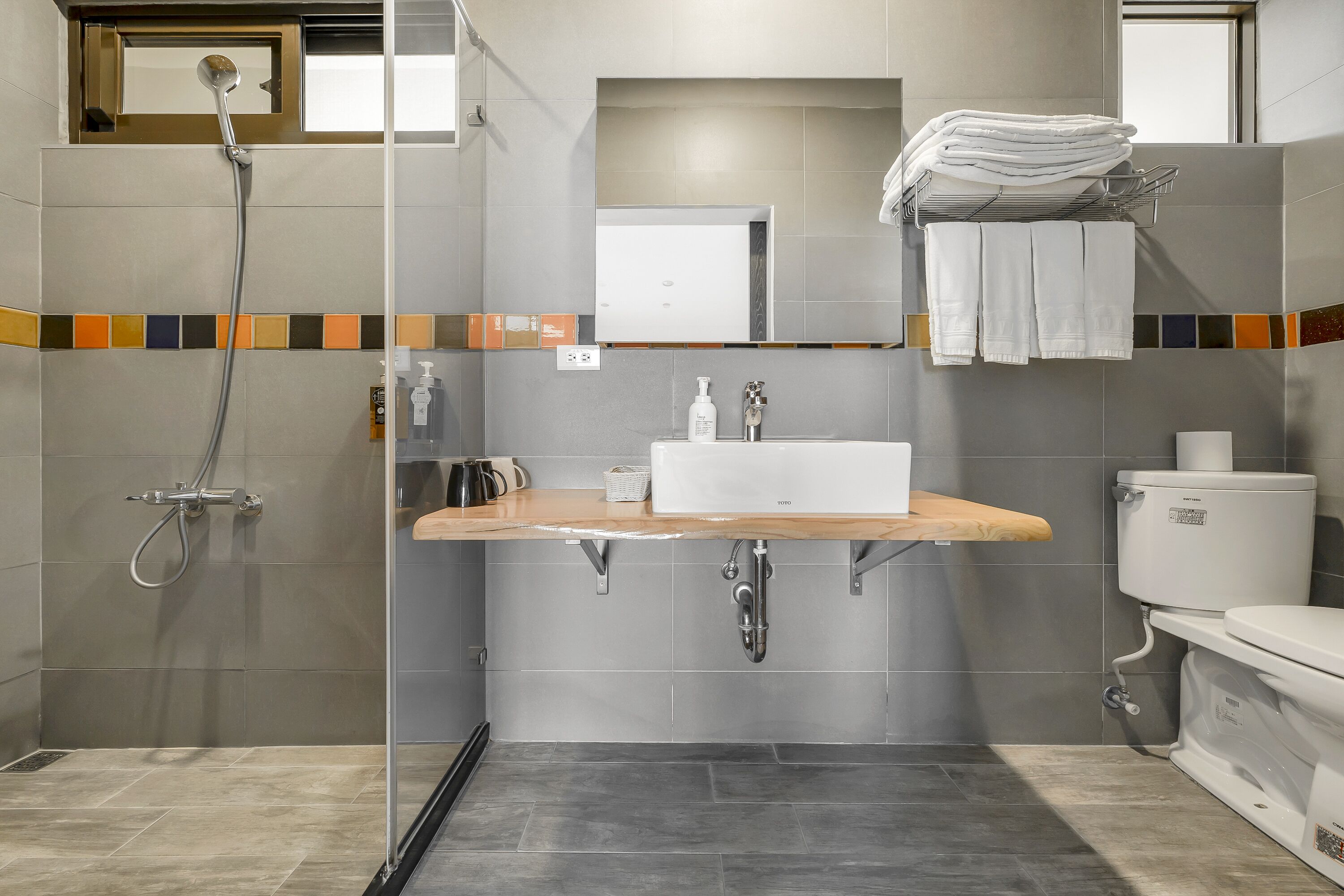 A modern bathroom with a shower, sink, and toilet.