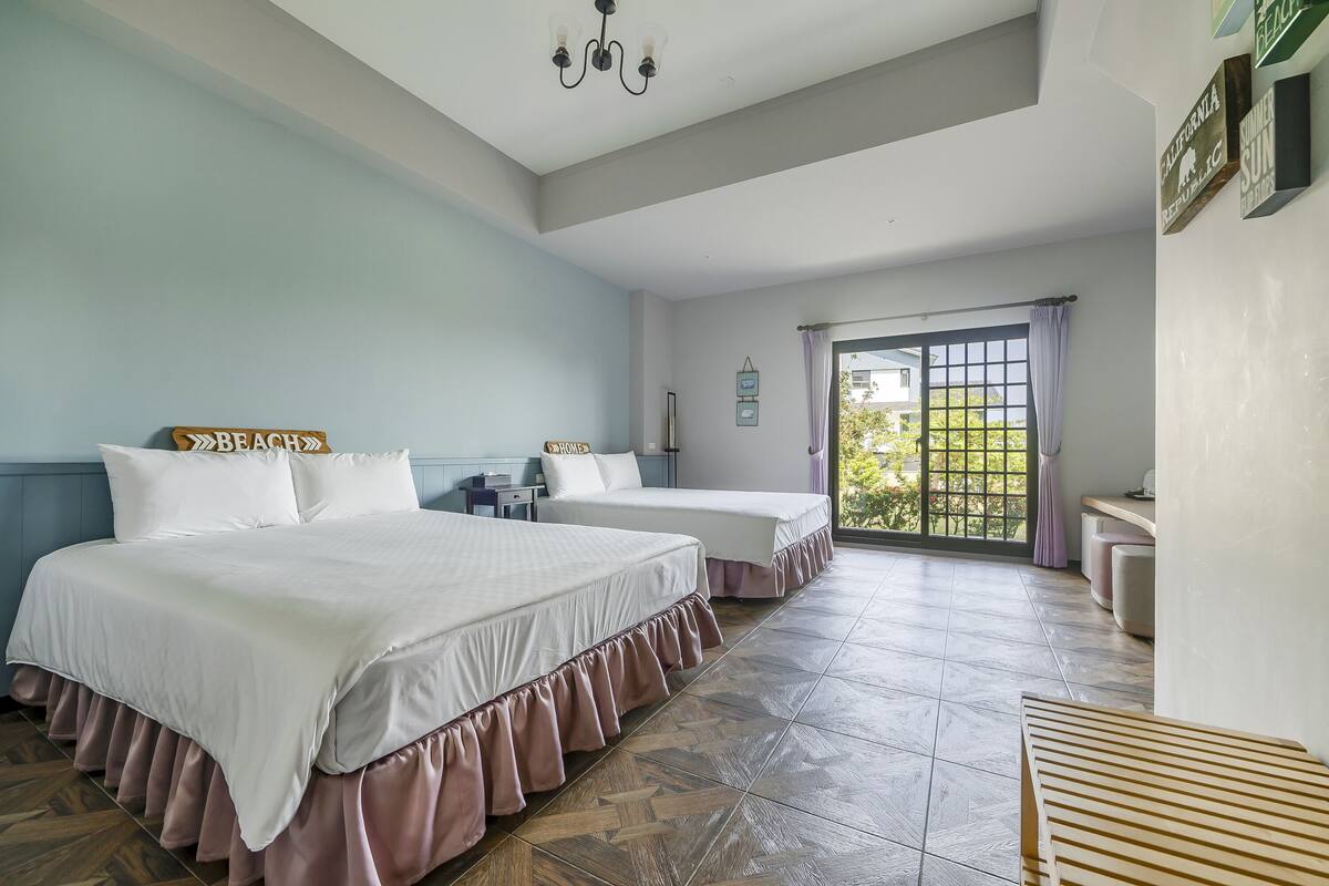 A bedroom with two beds, a large window, and a view of the outdoors.