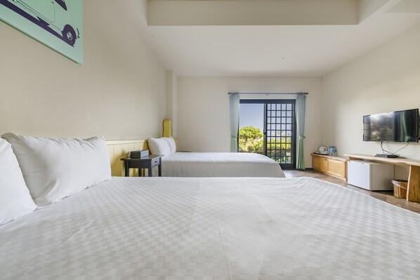 A hotel room with two beds, a desk, a TV, and a window with a view.