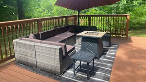 Una terraza con mobiliario de mimbre, una mesa y un paraguas rojo.