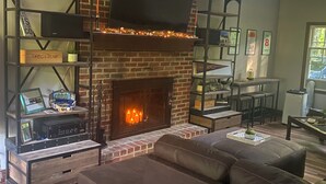 Una sala de estar con chimenea de ladrillo, un televisor de pantalla plana montado arriba y un sofá moderno.