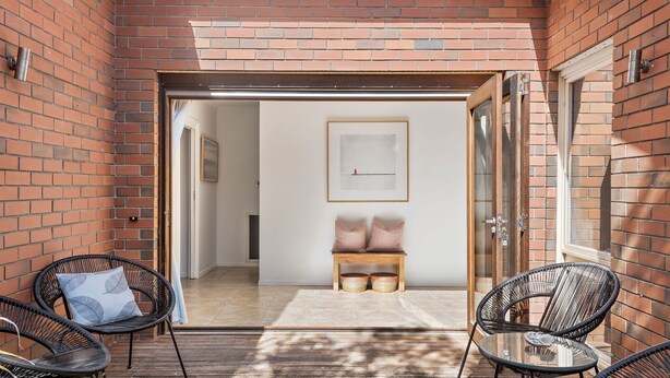 Un espace patio aménagé avec des chaises en osier, un banc en bois et une table en verre.