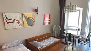 A modern hotel room with a bed, a sofa, a dining table with chairs, and artwork on the walls. - StraMo House (Bari)