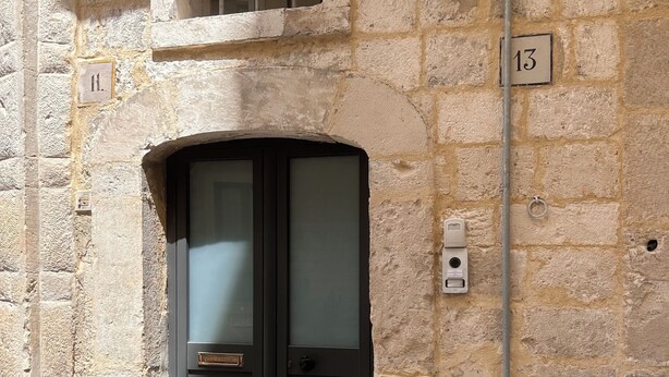 A stone building with a black door, a window with bars, and a number plate '13'. - StraMo House (Bari)