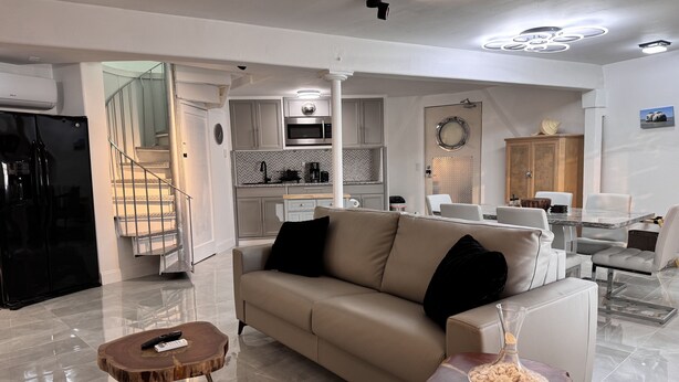 Una sala de estar moderna con un sofá beige, una mesa de centro y una zona de comedor con una mesa de vidrio.
