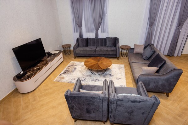 A modern living room with a sofa set, a coffee table, and a flat-screen TV. - Shitaye Suite Hotel (Addis Ababa)