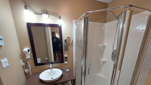 Ein Badezimmer mit einer gläsernen Duschkabine, einem Waschbecken mit Spiegel darüber und einem Waschtisch mit Aufbewahrungsboxen.