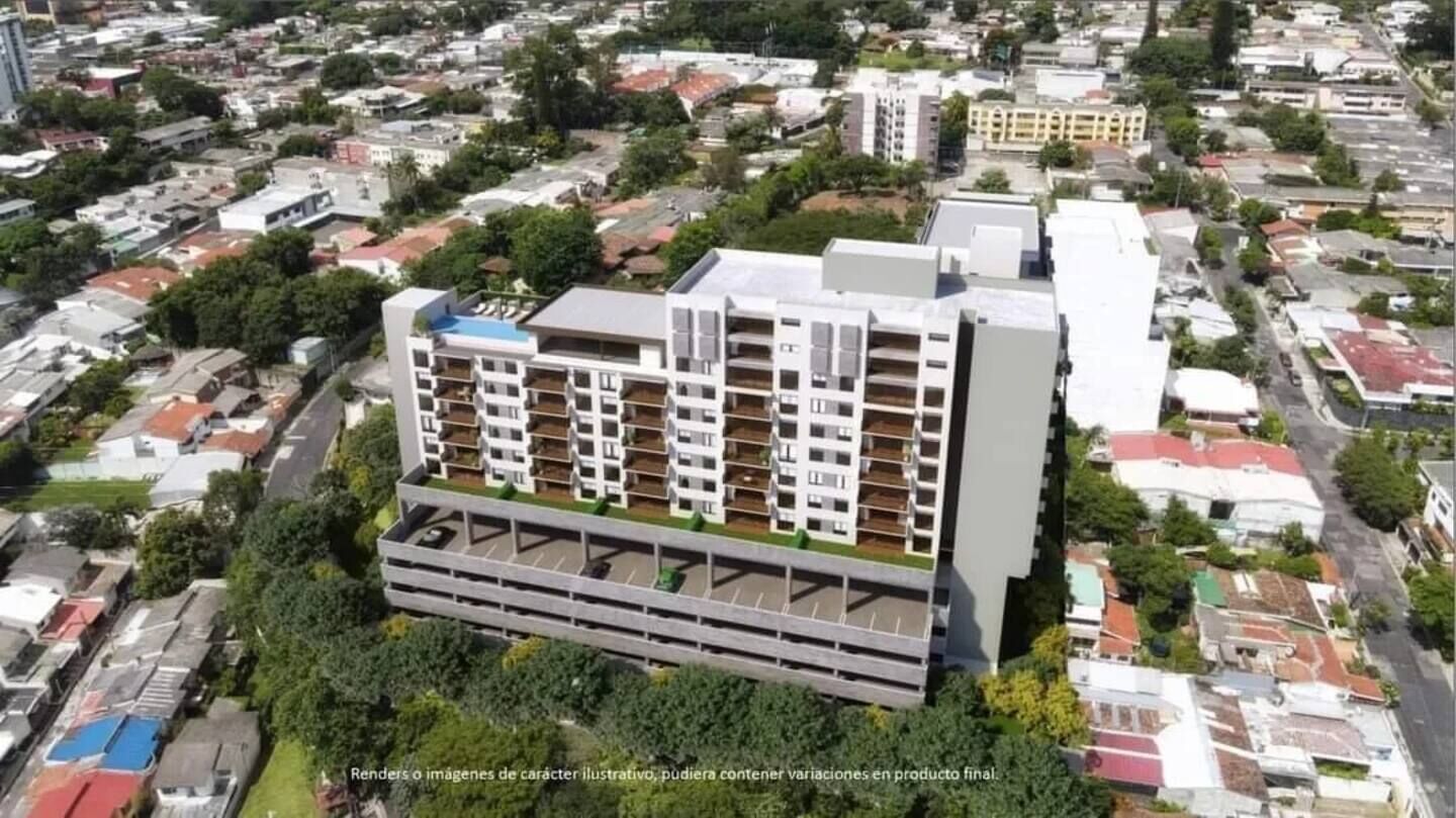 A modern multi-story building with a flat roof, surrounded by other residential buildings.