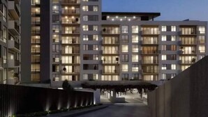 A modern hotel with multiple floors, balconies, and a well-lit exterior. - PanoramaTWR 2Brm Short walk to everything Pool&Gym

 (San Salvador)
