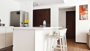 A modern kitchen with a central island, white bar stools, and a stainless steel refrigerator. - PanoramaTWR 2Brm Short walk to everything Pool&Gym

 (San Salvador)