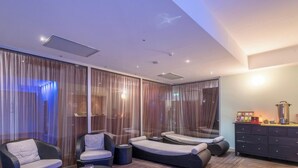 A modern room with a large sliding glass door, a sofa, a chair, and a small table with a coffee maker. - Hotiday Otranto Centro Storico (Otranto)