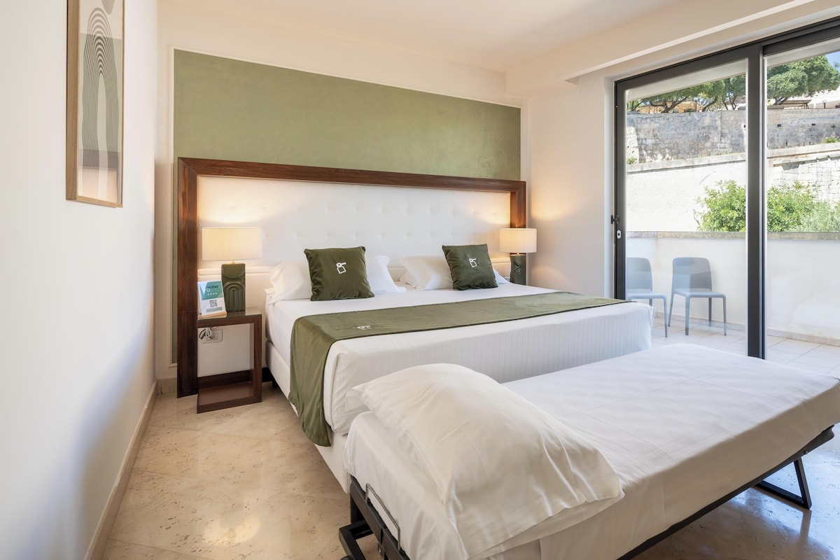 Habitación de hotel con dos camas, un ventanal grande y vistas al exterior.