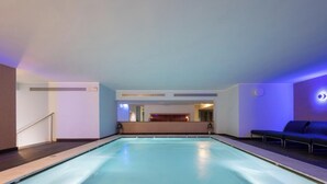 A pool area with a reception desk in the background, a staircase on the left, and a seating area on the right. - Hotiday Otranto Centro Storico (Otranto)
