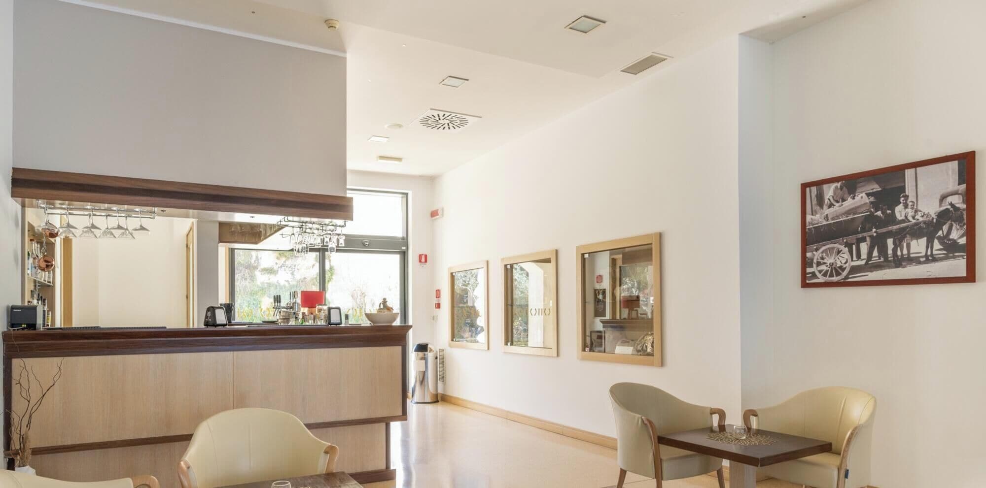 Un espace d’accueil avec un comptoir en bois, un coin salon avec deux fauteuils et des tableaux encadrés accrochés au mur.