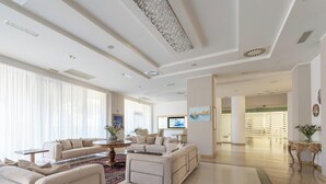 A spacious living room with a large window, a round coffee table, and a television. - Hotiday Otranto Centro Storico (Otranto)