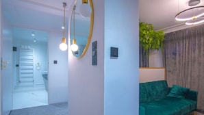 A modern living room with a green sofa, a large mirror, and a ceiling light fixture. - Motlawa Apartments - Old Town by the river, Fast Wifi (Gdansk)