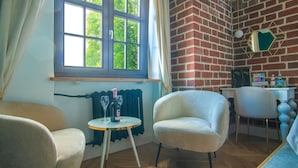 A cozy room with a brick wall, two white chairs, a small table with a bottle and glass, and a window with curtains. - Motlawa Apartments - Old Town by the river, Fast Wifi (Gdansk)