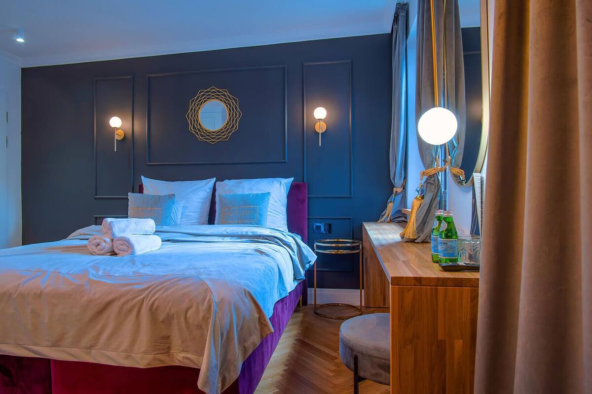 A bedroom with a bed, bedside table, and a mirror.