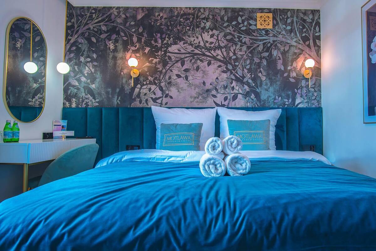 A hotel room with a bed, a desk, and a mirror.